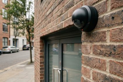 Caméra de surveillance visible installée en hauteur sur la façade en briques d'un bâtiment professionnel