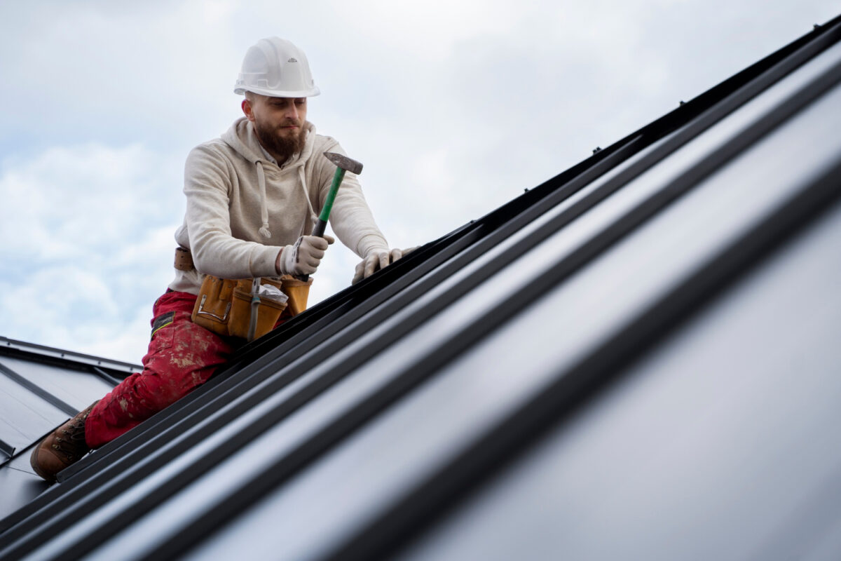 Homme travaillant sur le toit avec un marteau 